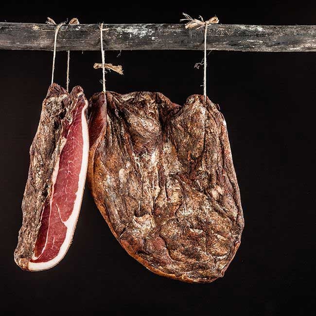Eine ganze und eine halbierte Seite Speck der Metzgerei Trockner aus Kollmann in Südtirol.